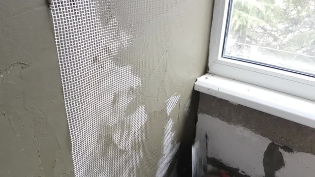 Repairman plastering wall with spatula. 	Forming of smooth hard surface on interior walls of apartment