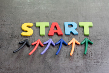 Business start begin the journey concept, colorful arrows point up to word START on blackboard cement wall to emphasize the important of initiation  thinking, brave and think out of the box