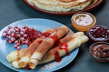 pancakes with berries, jam, honey and chocolate, sprinkled with powdered sugar and cinnamon