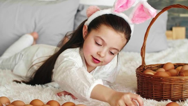 Happy girl playing with easter eggs in bed