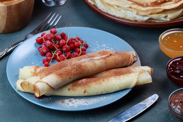 pancakes with berries, jam, honey and chocolate, sprinkled with powdered sugar and cinnamon