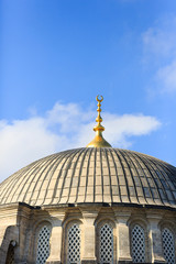 Fototapeta na wymiar Dome of a mosque with golden alem finial on a sunny day with blue skies.