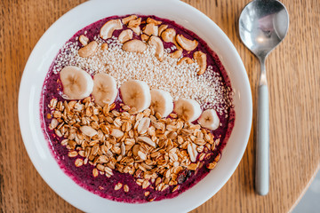 Beautiful blueberry banana smoothie bowl with a spoon on wooden table. Healthy breakfast concept.