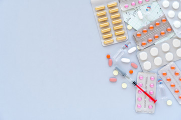 Pharmaceutical drugs, syringe and capsules on blue background