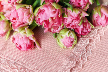 Pink plaid on the edges decorated lace. Bouquet of terry pink tulips is on top. The focus is on the plaid.
