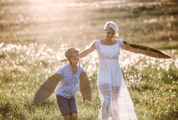 Young mother with small son playing on a meadow in nature.