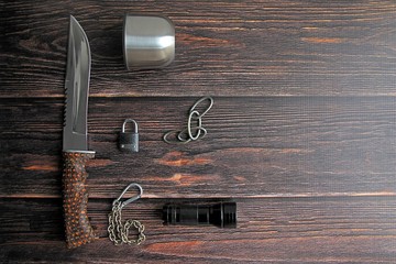 hunting knife, lantern, carbines, mug on a brown wooden background