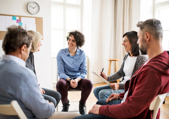 Men and women sitting in a circle during group therapy, talking. - obrazy, fototapety, plakaty