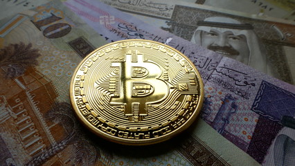 Bitcoin, an virtual currency in physical coin form, displayed on Saudi Arabian Riyal banknotes