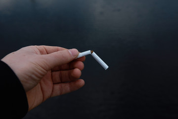 cigarette in hand against the background of water