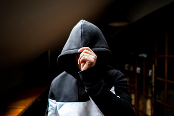 anonymous man in the dark hood standing in the mysterious pose f - obrazy, fototapety, plakaty