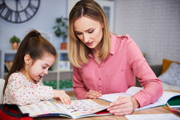 Mother helping her daughter with homework - obrazy, fototapety, plakaty