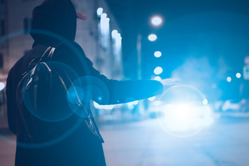 close up person hand hitch-hiking and waiting for a car stand on a highway in the night f