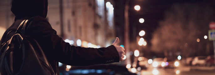 close up person hand hitch-hiking and waiting for a car stand on a highway in the night f