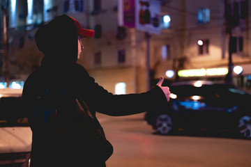 close up person hand hitch-hiking and waiting for a car stand on a highway in the night f