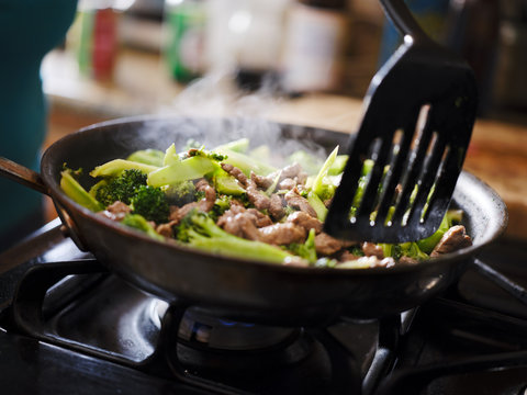 cooking beef and broccoli stir-fry in hot pain inside home kitchen