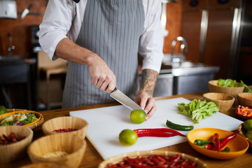 Mid section portrait of unrecognizable chef cutting vegetables while cooking spicy dish in restaurant, copy space