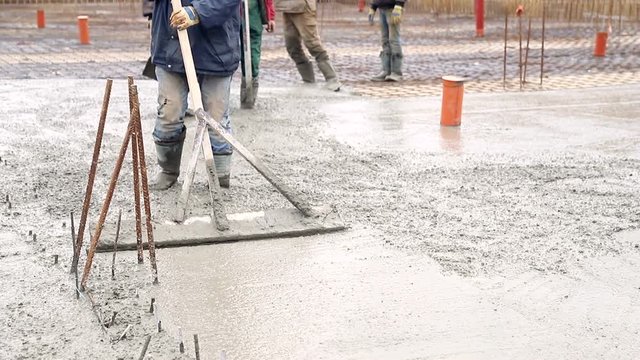 Worker aligns the level Soloslovo concrete. Pouring concrete mix from cement mixer on concreting formwork.