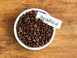 Bowl of Arabica coffee beans over an old wooden table
