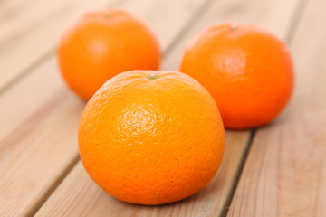three orange fruit citrus tankan against wooden background