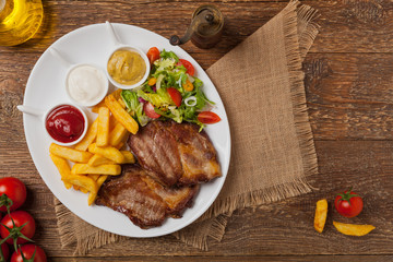 Grilled pork neck served with French fries and salad.