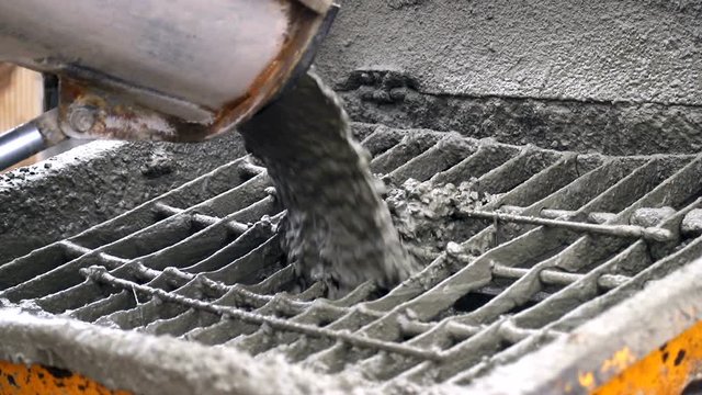 Concrete from the concrete mixer gets into the concrete feeder. Close-up of concrete particles moving slowly