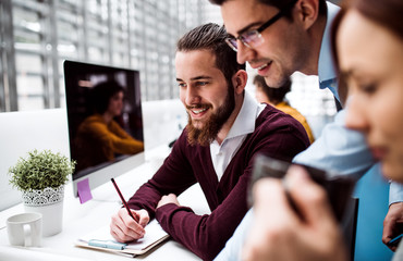 Group of young businesspeople working together in office, talking.