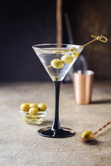 Cocktail martini with olives on gray stone background.