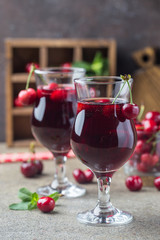 Homemade fresh cherry juice in a glass with fresh berries on rustic style background.