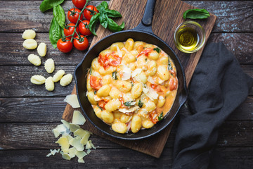 Homemade italian gnocchi with tomato, garlic, basil and mozzarella cheese on wooden table. Top view. Copy space. - obrazy, fototapety, plakaty
