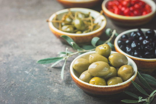 Italian appetizer from above. Mediterranean snack assortment. Black and green olives, capers, olive oil, onion and pepper.