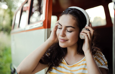 A young girl with headphones on a roadtrip through countryside, listening to music.