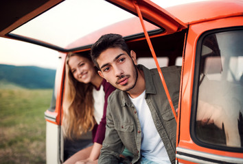 A young couple on a roadtrip through countryside, sitting in minivan.