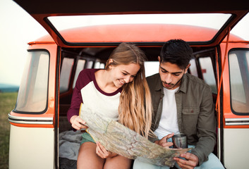 A young couple on a roadtrip through countryside, looking at a map.