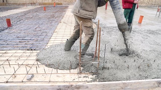 Pouring concrete mix from cement mixer on concreting formwork. A group of workers pouring concrete on a construction site