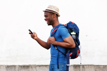 Side of happy african american tourist man holding mobile phone