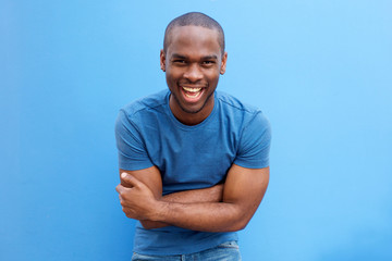 handsome young african american man laughing with arms crossed