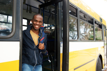 happy young african american travel man with bag getting off bus