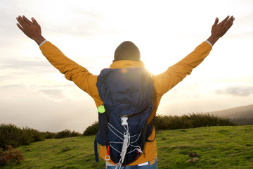 back of hiker with arms spread open during sunset