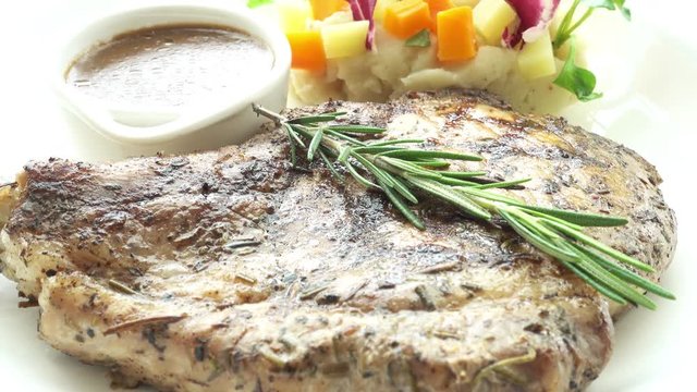 Close up of a steak with rosemary, mashed potatoes, and au jus