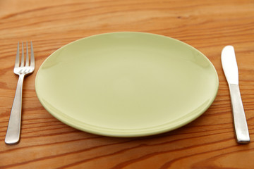 empty green dish on the wooden table with cutlery
