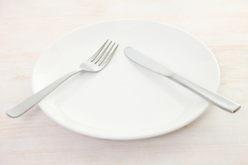 white dish on the white wooden table with cutlery meaning PAUSE