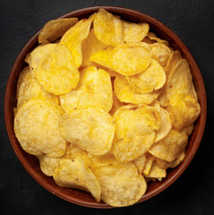 Crispy chips in a bowl on a stone background