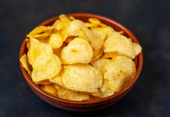 Crispy chips in a bowl on a stone background