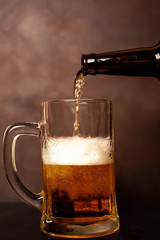 pours beer into a glass on an old stone