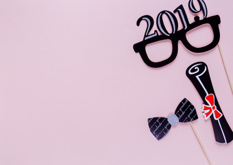 Creative background with photobooth props for graduation: hats, diploma, glasses, lips on pastel...