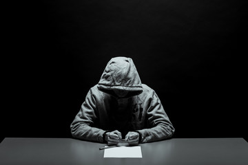Hands of the criminal in handcuffs write a handle on paper. Sincere confession, request, statement....