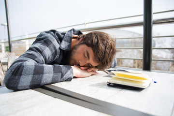 Tired student sleeping with his head rested on table