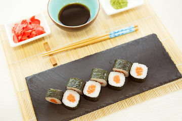Closeup of sushi rolls with chopsticks. Roll with salmon, avocado, cucumber.