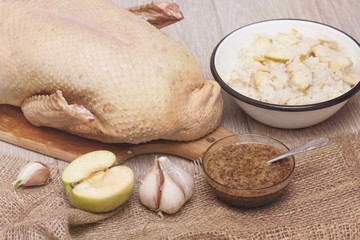 Fototapeta premium Preparing stuffed duck, old photo style. Fresh raw duck with rice and apples.